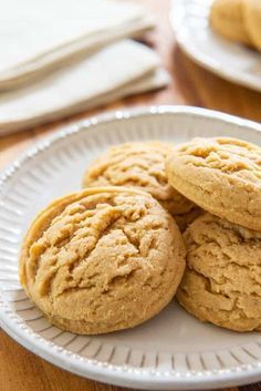 three cookies on a white plate sitting on a wooden table