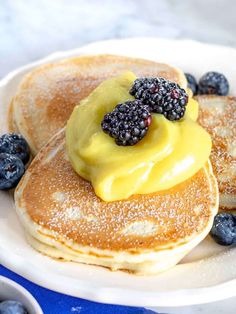 pancakes topped with berries and butter on a white plate