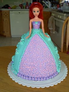 there is a cake that looks like a princess doll on top of a table in the kitchen