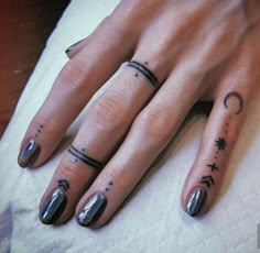 a woman's hand with two small tattoos on her fingers and the other finger