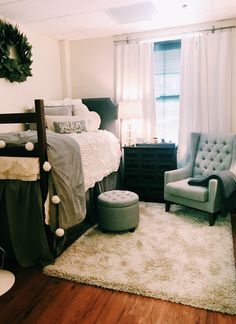 a bedroom with a bed, chair and rug on the wooden floor next to a window