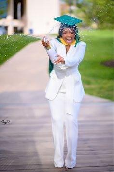 a woman in a white suit and green cap splashing water on her head while standing outside