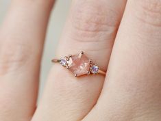 a woman's hand with a pink diamond ring on it