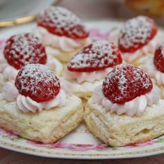 strawberry shortcakes on a plate with powdered sugar and strawberries in the middle