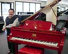 a man sitting at a red piano in an office