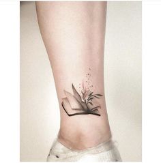 a book tattoo on the ankle with a plant growing out of it's pages