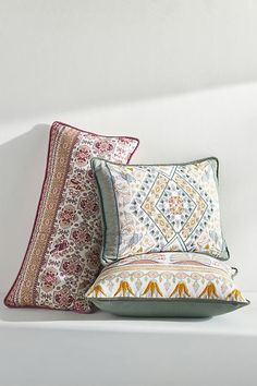 three decorative pillows on a white surface