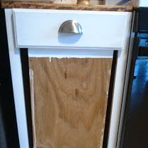 a wooden cabinet with a metal knob on the front and bottom panel is being worked on