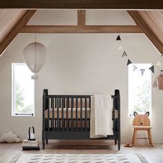 a baby's room with a black crib, white rug and wooden flooring