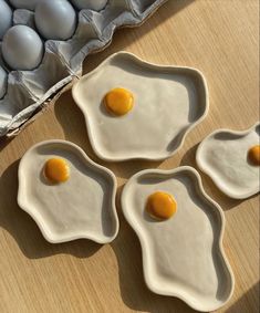 four eggs are in the shape of an egg shell on a wooden table next to some eggs