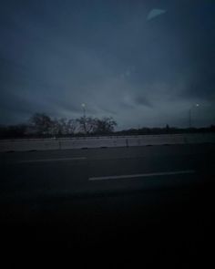 the sky is very dark and cloudy at this time of night as seen from an empty highway