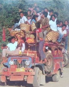 a group of men riding on the back of an old jeep with baskets on top