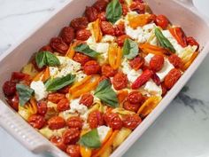 a casserole dish with tomatoes, cheese and basil leaves on the top is ready to be eaten