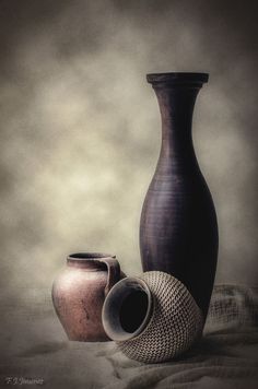 two vases sitting next to each other on top of a cloth covered tablecloth