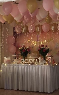 a table topped with lots of pink and gold balloons