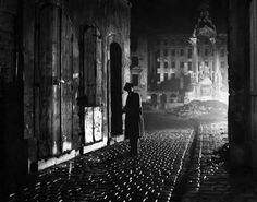 a man standing in the middle of a street at night with his back to the camera