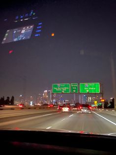 cars driving down the highway at night with city lights in the background