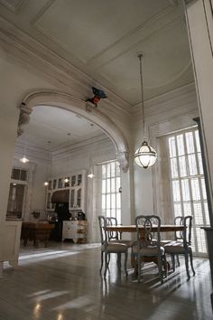 a dining room table and chairs in front of two windows with arched arches on the ceiling