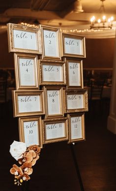 there is a gold frame with flowers on it and the table numbers are placed next to each other