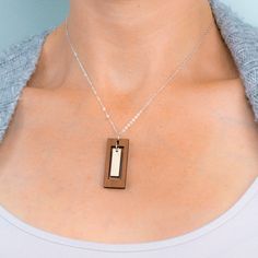 "This rectangular bar necklace offers the boldness of a geometric design combined with the delicacy of a long, slender composition. The outer rectangle encompasses an inner panel for a multi-faceted design with movement and visual interest. Two tones of intricately cut wood - walnut and maple - give additional texture to the piece. Wood and silver necklaces can be dressed up or down, making them the perfect complement to any outfit! Pair with the matching rectangle earrings for a coordinated loo Wood And Resin Jewelry, Inspirational Keychains, Laser Cut Necklace, Rectangle Necklace, Faceted Design, Rectangle Earrings, Wood And Resin, Bespoke Gifts, Artisan Gift