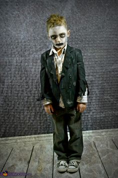 a young boy dressed up in a suit and tie with makeup painted on his face