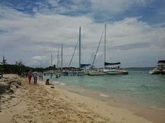 people are walking on the beach near boats