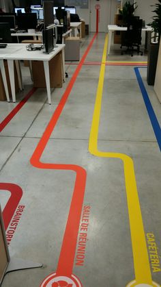 an office floor painted with yellow and red lines in the center, along with two computer desks on either side