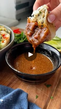 a person dipping some food into a bowl