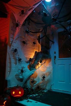 halloween decorations in front of a house with spider webs and pumpkins on the door