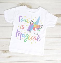 a white t - shirt with the words four is magic written in rainbow letters on it