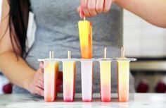 the woman is making popsicles out of fruit juices in plastic cups with toothpicks sticking out of them