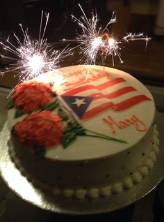 a white cake with red flowers and sparklers on top