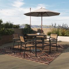 an outdoor table and chairs on a rug with an umbrella over it in the middle of a patio