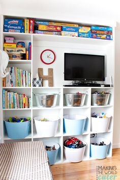 a white bookcase filled with lots of books and toys next to a flat screen tv