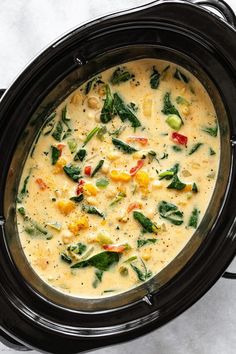 an overhead view of a crock pot filled with soup and vegetables on a white surface