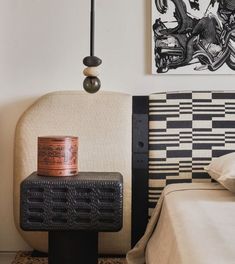 a bedroom with an upholstered headboard and footstool next to a painting on the wall