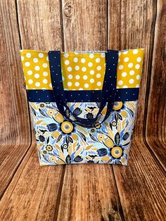 a yellow and blue tote bag sitting on top of a wooden table with polka dots