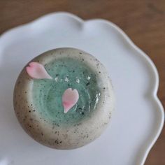 a cupcake with pink hearts on it sitting on a white plate