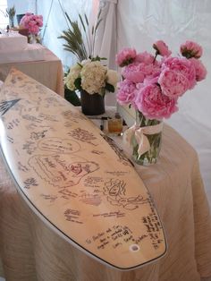 a surfboard is sitting on a table with flowers in vases