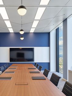 an empty conference room with blue walls and white paneling, along with a large flat screen tv mounted on the wall