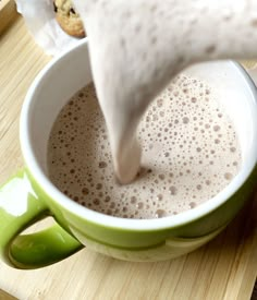 a person pours milk into a green cup