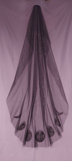 a purple veil is hanging up on a white sheet with sequins and beads