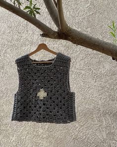 a crocheted top hanging on a tree branch