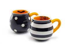 two black and white striped coffee mugs with orange rimmed handles, one has a bat on it