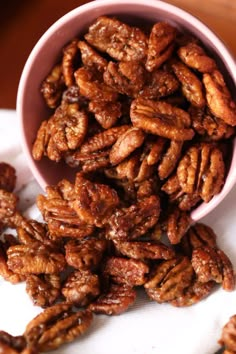 a pink bowl filled with pecans sitting on top of a table