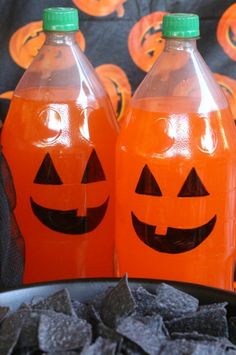 two plastic bottles with jack - o'- lanterns on them sitting next to black chips