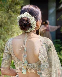 the back of a woman's dress with flowers in her hair and an elaborate headpiece