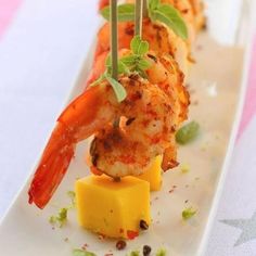 a long white plate topped with shrimp and cheese on top of a striped table cloth