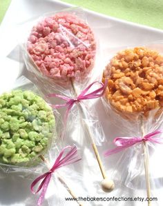 three candies are wrapped in cellophane and tied with pink ribbon on a white tray