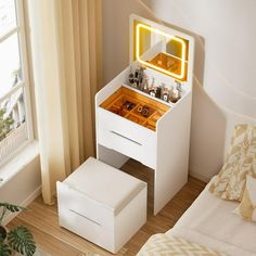 a bedroom with a white vanity and mirror on the wall next to a bed in front of a window